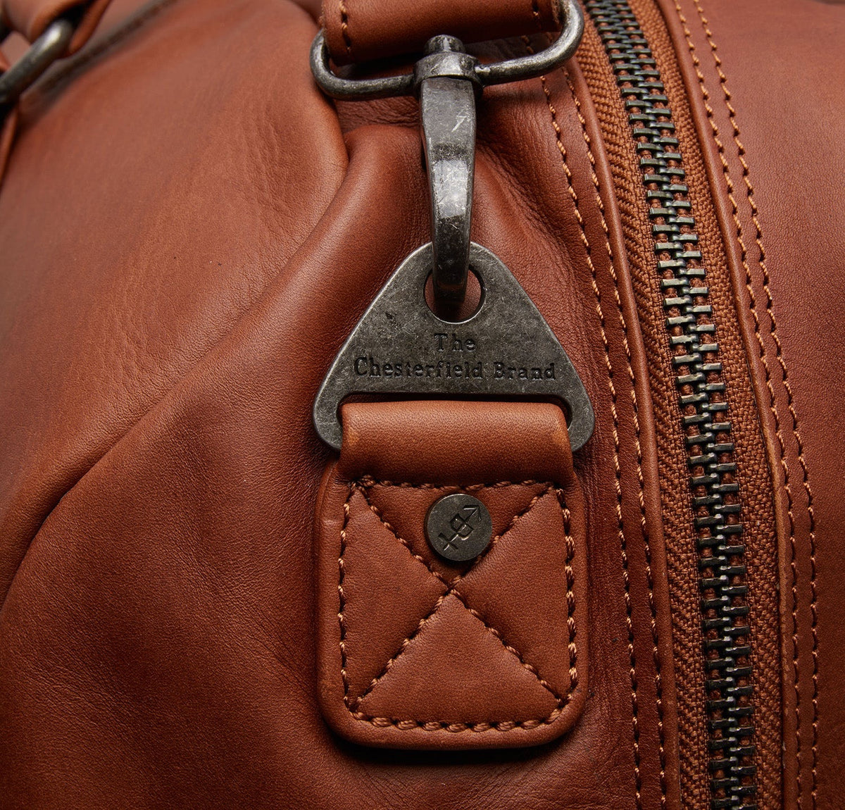 Chesterfield Perth Cognac – Detailansicht Metall-Logo-Anhänger am Reißverschluss, cognacfarbenes Leder