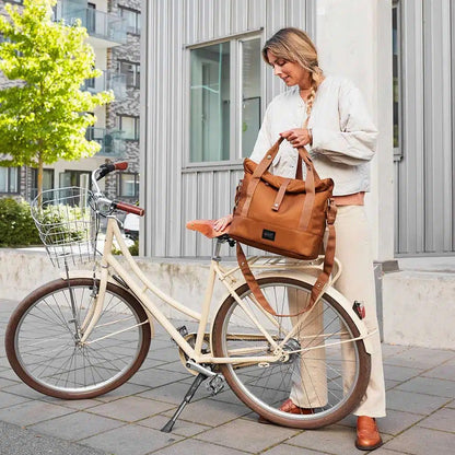Frau nimmt City Bike Satchel braun vom Fahrrad – Umwandlung zur Schultertasche in urbaner Umgebung